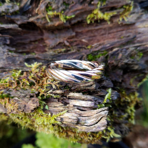 Close-up of the Rose and White Gold Twisted Wire Wedding Ring, made in Ireland by Elena Brennan. This Irish wedding ring is perched on tree bark.