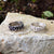 Blackened and shiny silver bubble rings sitting on flat rock surface.