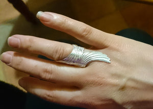 A hand wearing the sterling silver angel wings ring, part of Elena Brennan's angel jewelry collection