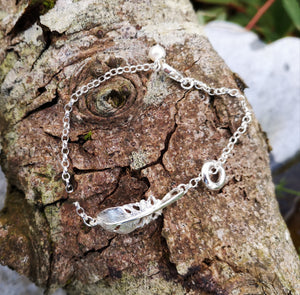The "Cherish" Baby Angel Feather Bracelet from Elena Brennan's 'My Angel' collection, is made from Irish Sterling Silver. It is photographed here against tree bark