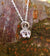 Sterling silver baby feet and halo pendant, part of Elena Brennan's angel jewelry collection. Photographed here against tree bark.