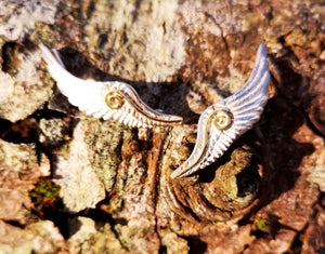 Handmade sterling silver Angel Wings Ear Cuff with spiral gold detail, displayed on tree bark. These earrings are part of the Irish My Angel jewelry collection
