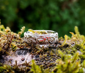 A closer look at the Irish handmade Claddagh wedding ring band handmade from Sterling Silver by Elena Brennan Jewellery. This Celtic jewelry piece is perched on a mossy branch
