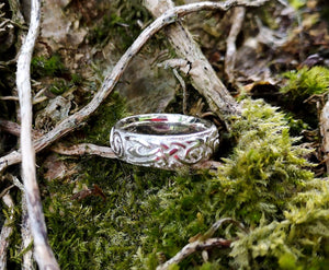 This Irish Claddagh wedding ring band is handmade from Sterling Silver by Elena Brennan Jewellery. This Celtic jewelry piece is perched on tree moss