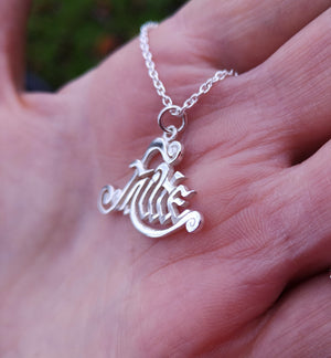 This meaningful Irish sterling silver Fáilte Pendant from the side. This Gaelic welcome necklace is perched on the palm of a hand