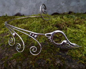 Children of Lir sterling silver torc necklace, featuring a Celtic swan. This torc jewelry piece is sitting on a mossy tree branch
