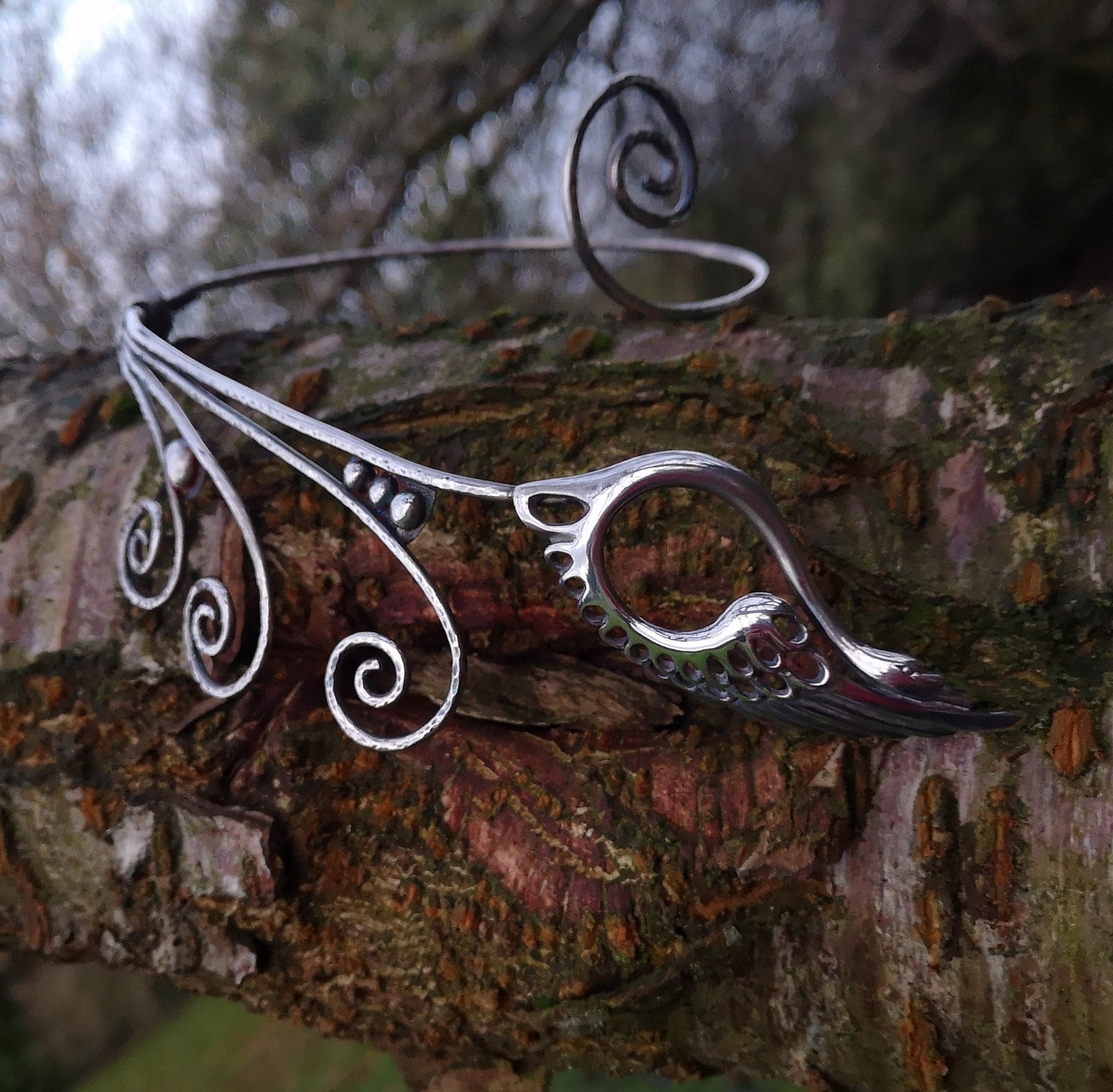 Children of Lir sterling silver torc necklace, featuring a Celtic swan. This torc jewelry piece is sitting on a tree branch