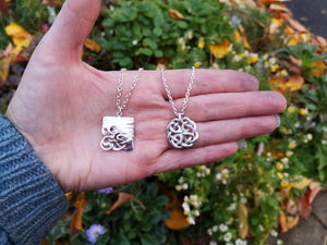 Celtic knot jewelry pieces displayed on the palm of a hand. The Celtic Love Knot Pendant is on the right