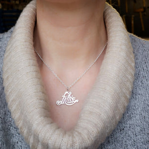 A woman wearing the Sterling Silver Fáilte Pendant. This Gaelic welcome pendant is handcrafted in Ireland by Elena Brennan