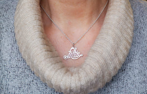 A woman wearing the Sterling Silver Fáilte Pendant. This Gaelic welcome pendant is handcrafted in Ireland by Elena Brennan