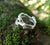 A sterling silver family birthstones ring in the shape of twigs that can also function as an Irish wedding ring or promise ring. The ring is sitting on a mossy surface.