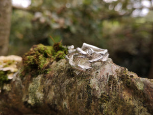 A sterling silver family birthstones ring in the shape of twigs that can also function as an Irish wedding ring or promise ring. The ring is sitting on a tree branch.