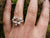 A hand showing off the twiggy family birthstone ring, made of sterling silver. It can also function as an Irish wedding ring or promise ring.