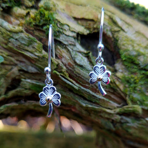 Sterling Silver Shamrock Stud Earrings, Irish jewellery handcrafted by Elena Brennan, perched on a mossy tree branch. Perfect First Holy Communion earrings gift for a special little girl