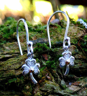 Sterling Silver Shamrock Stud Earrings, Irish jewellery handcrafted by Elena Brennan, perched on a mossy tree branch. Perfect First Holy Communion earrings gift for a special little girl