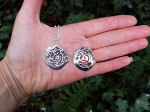 Hand showing off the An Cabhán pendants made of sterling silver, inspired by the beautiful Co. Cavan.