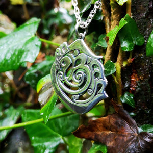 The sterling silver An Cabhán pendant hanging against a vine backdrop.