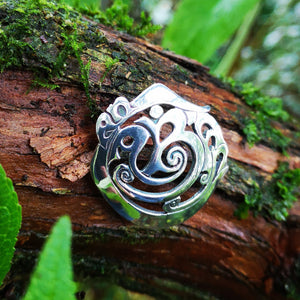 Detail of the Cavan (An Cabhán) Brooch made of sterling silver, sitting on tree bark. An Irish design jewellery piece is inspired by the landscape of County Cavan.