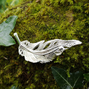 Silver angel feather brooch sitting on mossy tree bark. Part of the My angel jewellery collection, made in Cavan.