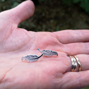 Small angel feather stud earrings made of sterling silver.