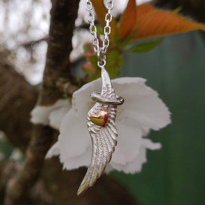 Angel whisper wing halo and heart pendant with white flower in the background. Part of the My Angel jewellery collection.