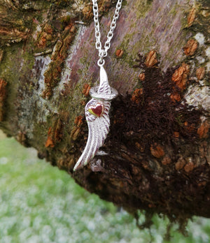 The angel wing and halo pendant hanging from a tree branch. This angel jewellery is handmade in Ireland.