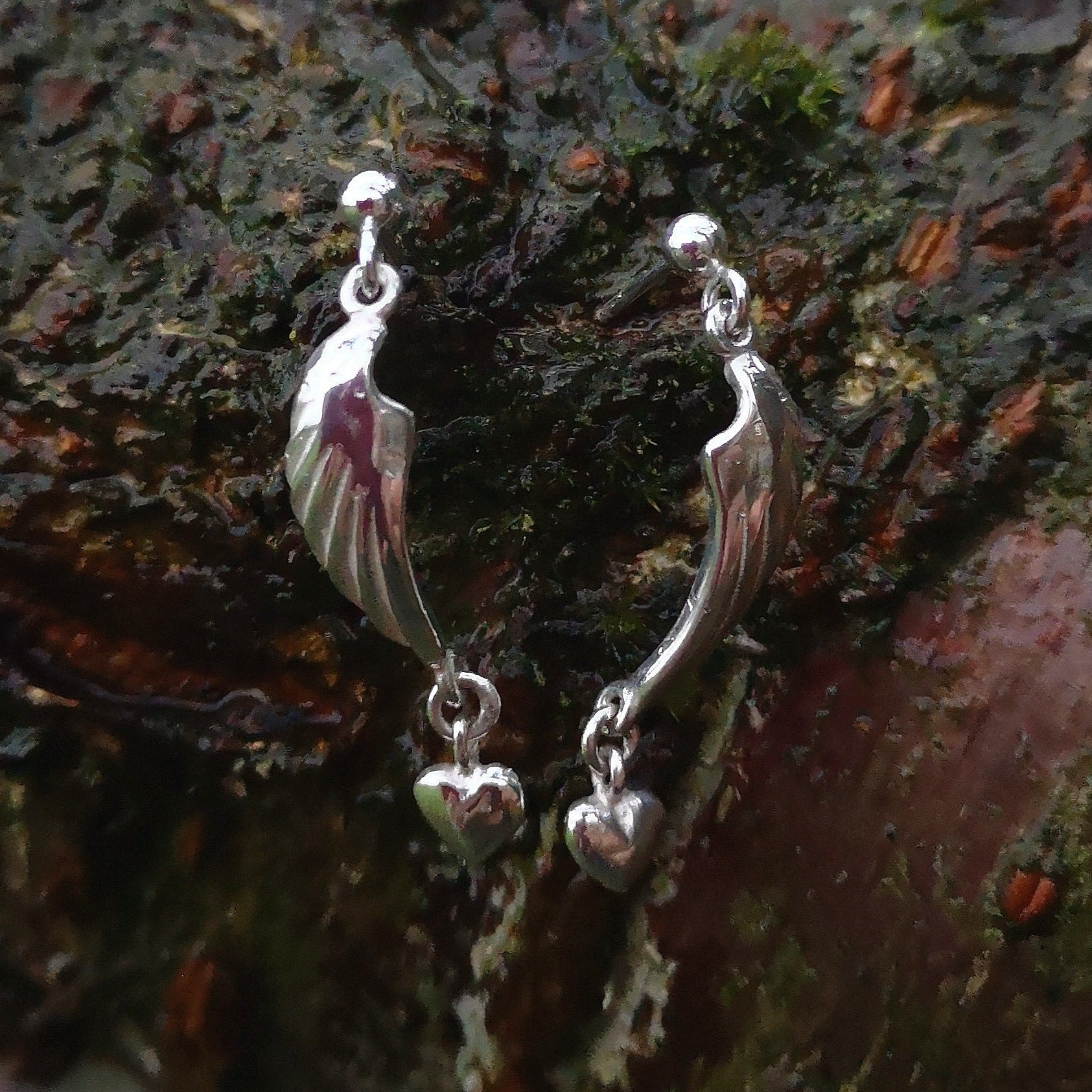 Angel Hug Earrings handmade from Sterling Silver by Irish Jewellery Designer Elena Brennan. These angel wing earrings are displayed against tree bark and are part of the My Angel jewellery collection.