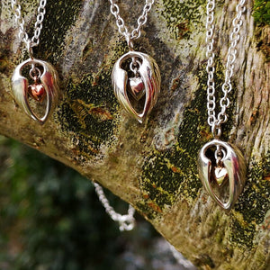Three sterling silver Angel Hug pendants with silver, gold and rose-gold hearts. They are part of the My Angel Jewellery Collection handmade by Elena Brennan.