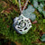 The Cavan 'An Cabhán' pendant made of sterling silver is hanging against mossy tree bark.
