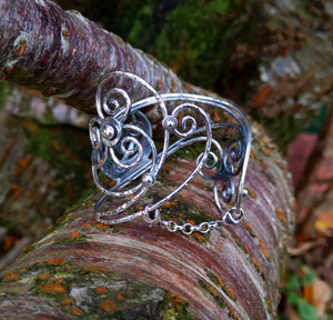 Sterling Sliver Children of Lir Four Swan Bangle sitting on tree branch. Handcrafted in Cavan, Ireland and inspired by Irish mythology.