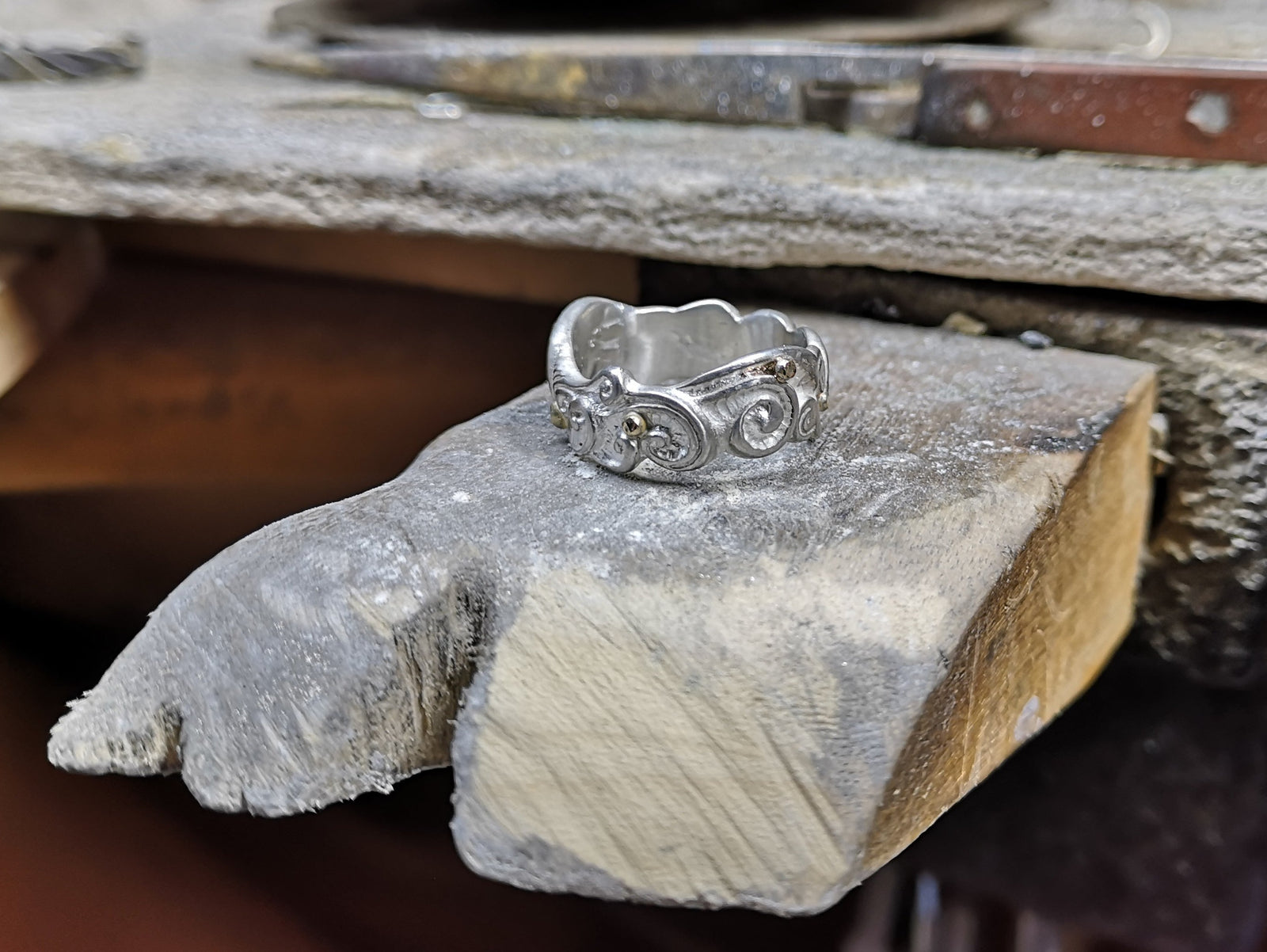 Celtic spirals Irish wedding ring handcrafted from sterling silver sitting on wood block.