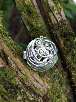 Children of Lir silver swan pendant with 4 swan design and a gold heart sitting on mossy tree bark. Made in Ireland.