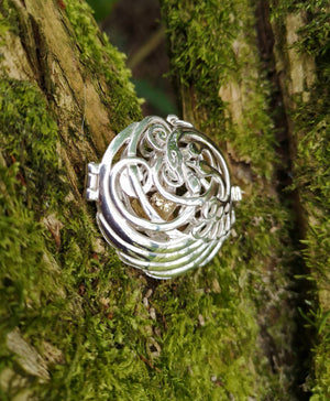 Children of Lir silver swan pendant with 4 swan design and a gold heart sitting on mossy tree bark. Made in Ireland.