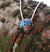 Journey of Life medium size pendant with blue sheen hanging on tree branch. Handmade in Cavan, Ireland.