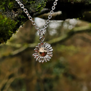 Gold and silver daisy pendant hanging from branch