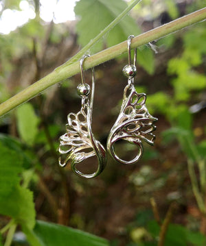 Handmade sterling silver Swan Drop Earrings are handcrafted by Irish Jewellery Designer Elena Brennan. The earrings are hanging from a twig.