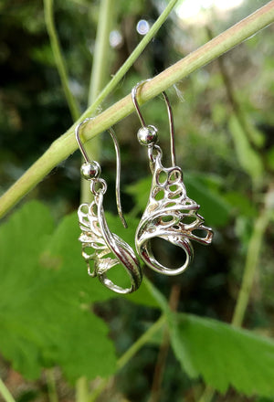 These handmade Swan Drop Earrings are part of Elena Brennan Jewellery's Children of Lir Collection. The earrings are hanging from a twig.