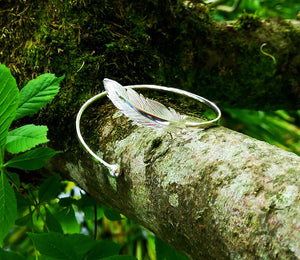 The sterling silver Earth Angel Feather Bangle is sitting on a branch. This Irish angel bangle is part of Elena's My Angel jewellery collection.