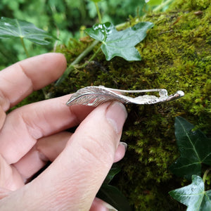 Side view of silver angel feather brooch sitting on mossy tree bark. Part of the My angel jewellery collection, made in Cavan.