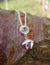 Sterling silver baby feet and halo pendant, part of Elena Brennan's angel jewellery collection. This angel pendant is hung against a tree branch.