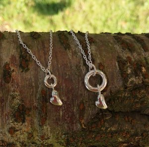 Silver halo and heart pendants on a tree branch. These necklaces are part of the Irish My Angel jewellery collection.