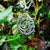 The sterling silver An Cabhán pendant hanging against a vine backdrop.