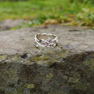 The sterling silver Celtic Spirals Wedding Ring perched on a smooth rock outside.