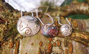 Journey of Life concave Irish pendant collection sitting on a tree branch.