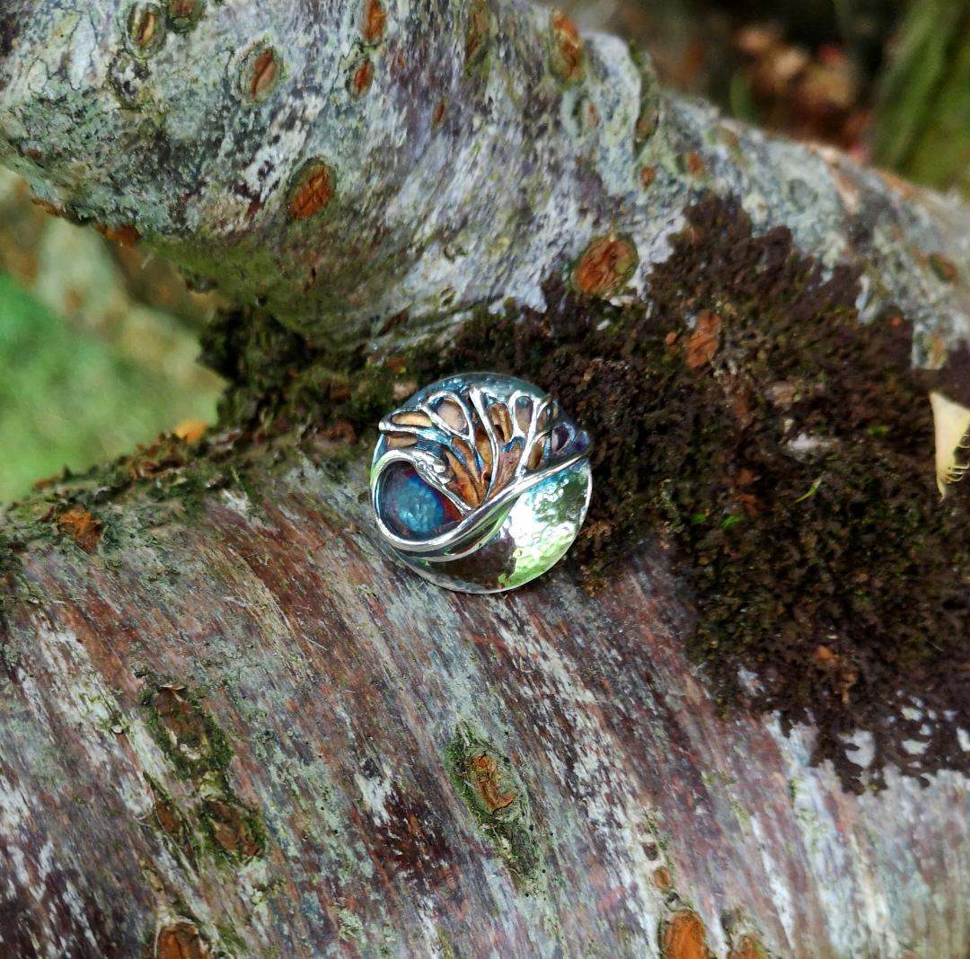 The Swan Lapel Pin is a domed and beaten sterling silver disc, from the Children of Lir jewellery collection.