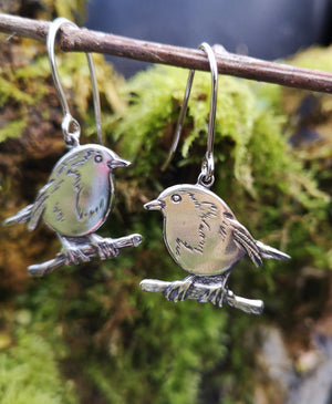 Robin Red Breast Communion earrings hanging on a twig. These sterling silver First Holy communion earrings are made by Elena Brennan Jewellery.