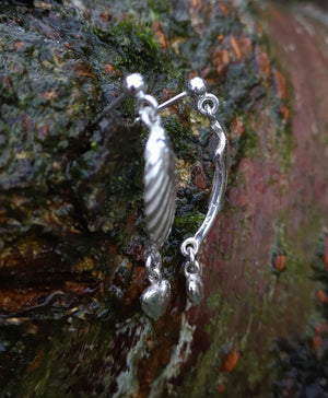 Side view of the sterling silver Angel Hug Earrings handmade by Irish Jewellery Designer Elena Brennan. These angel wing earrings are displayed against tree bark and are part of the My Angel jewellery collection.