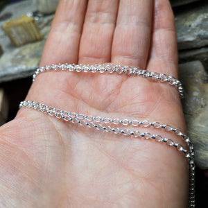 Sterling silver pendant chains sitting on a hand.