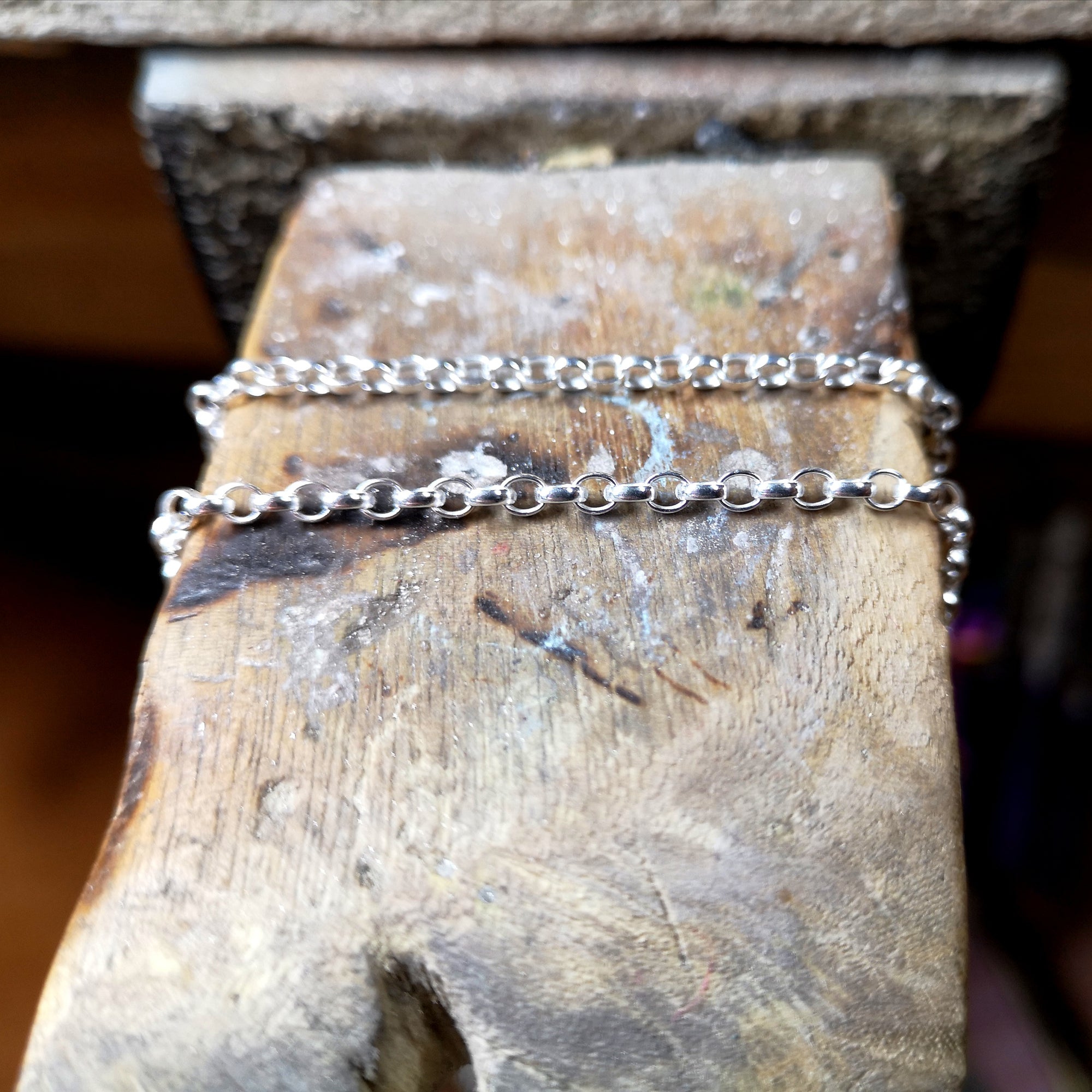 Sterling silver chains hanging on a wooden table.