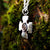 Side view of silver Crux Quadrata pendant hanging against mossy tree bark.